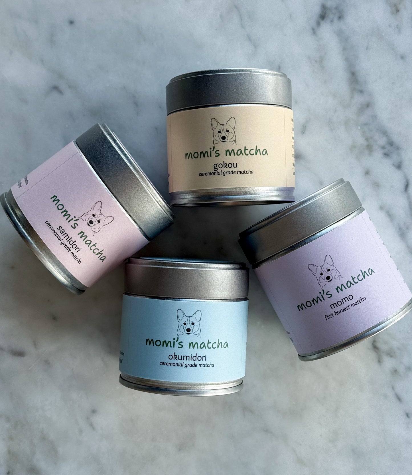Four tins of 'momiji matcha' on a marble surface